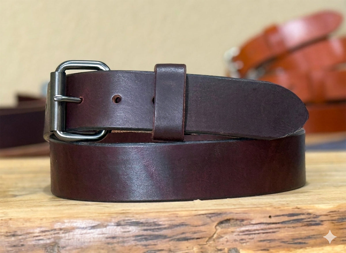 Burgundy leather belt with a silver buckle on a wooden surface