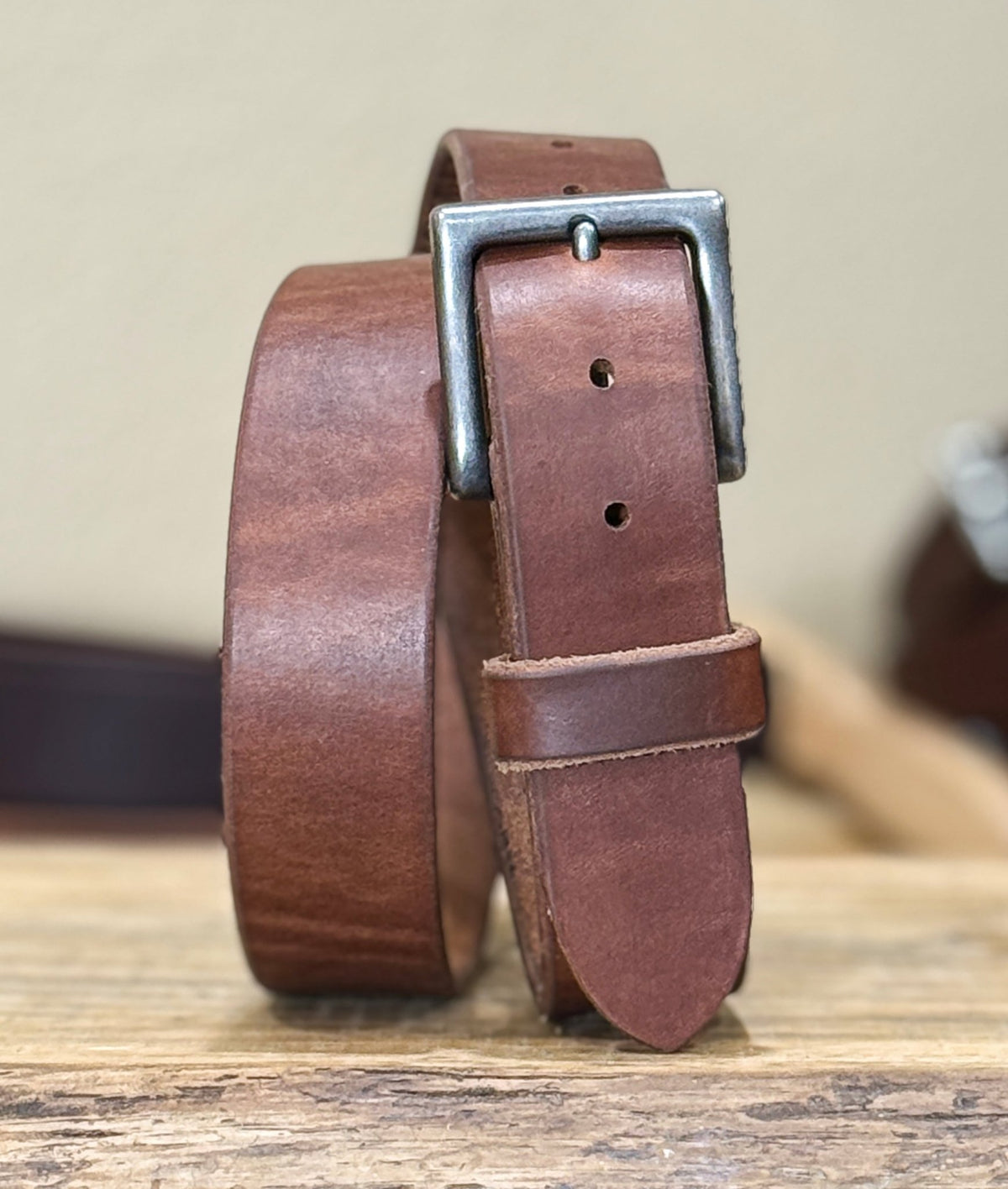 Brown leather belt with a silver buckle on a wooden surface