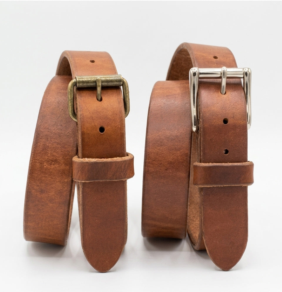 Two russet harness leather belts with brass and silver buckles on a white background