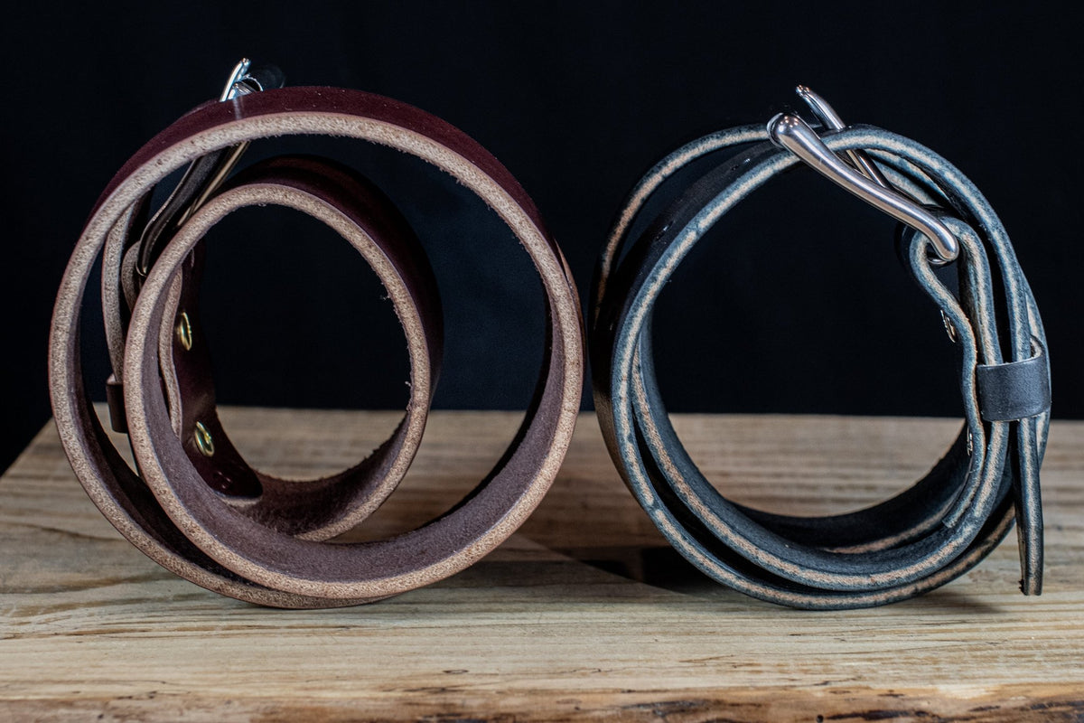Side view of black and brown Maverick raw-edge leather belts coiled to show their natural leather edges.