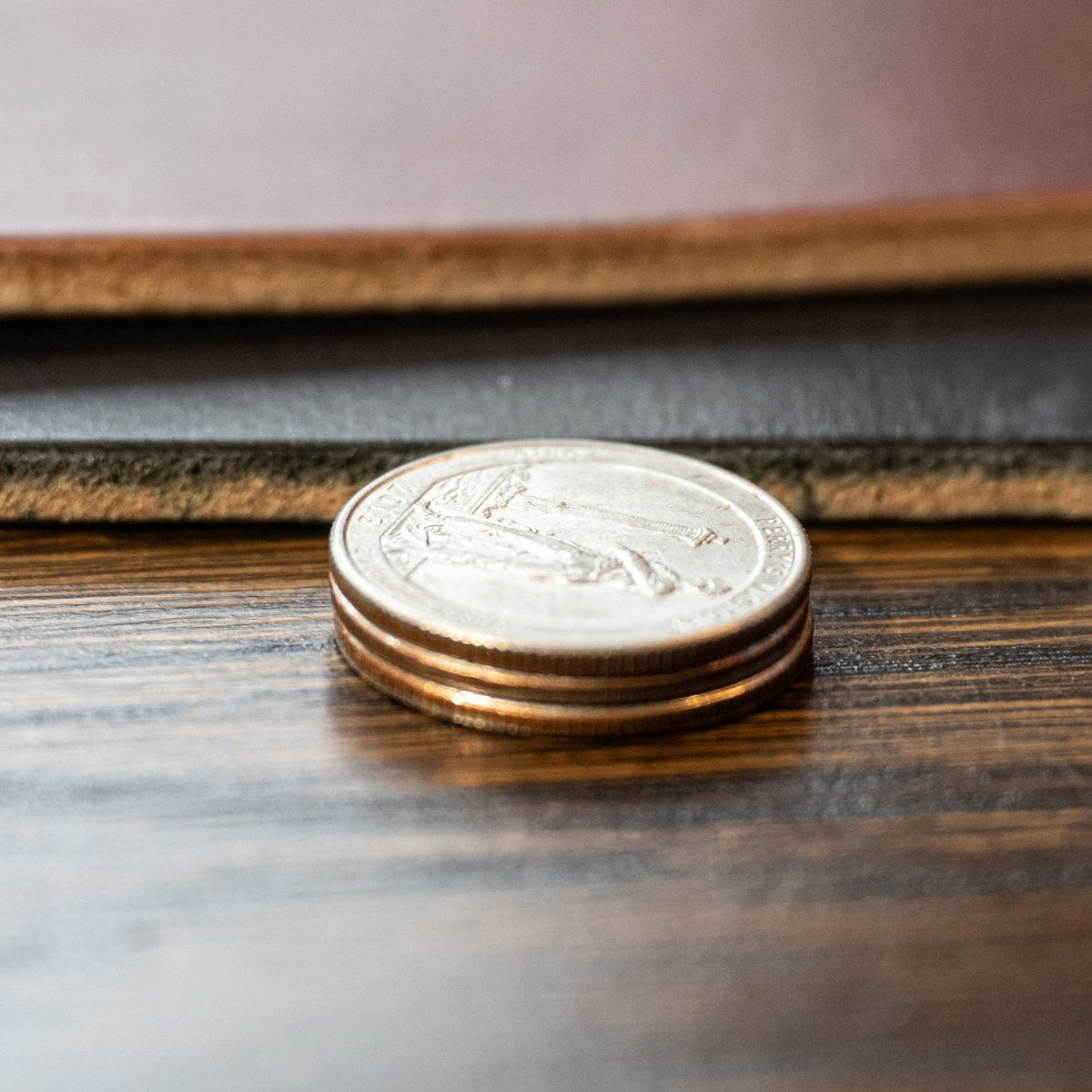 Black and brown Maverick raw-edge leather belt straps beside stacked coins for a thickness comparison.
