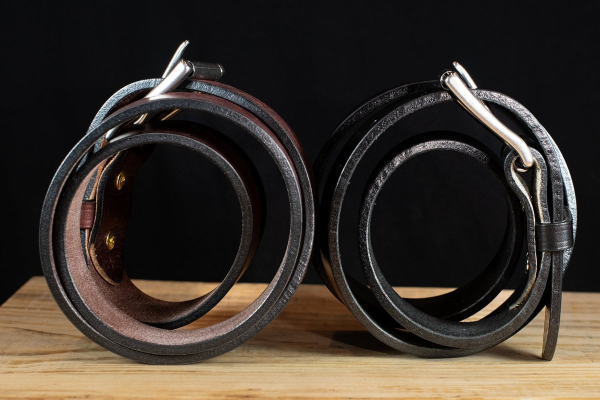 Side view of black and brown Wrangler creased-edge leather belts coiled to show their leather thickness.