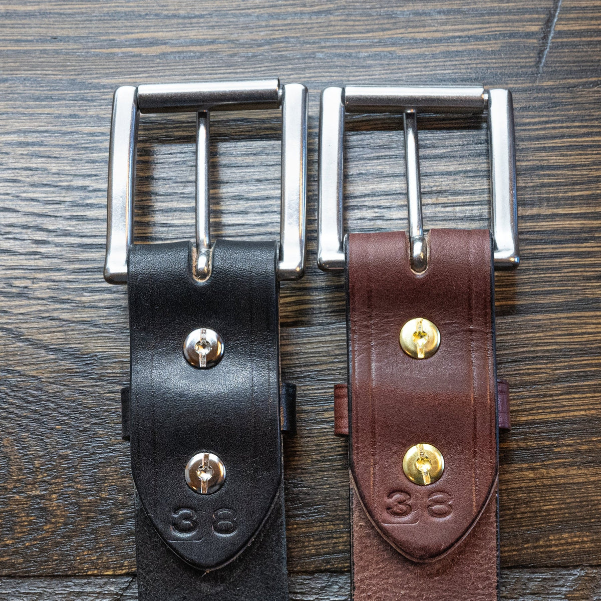 Back of black and brown Wrangler creased-edge leather belts showing Chicago screws and size stamps.
