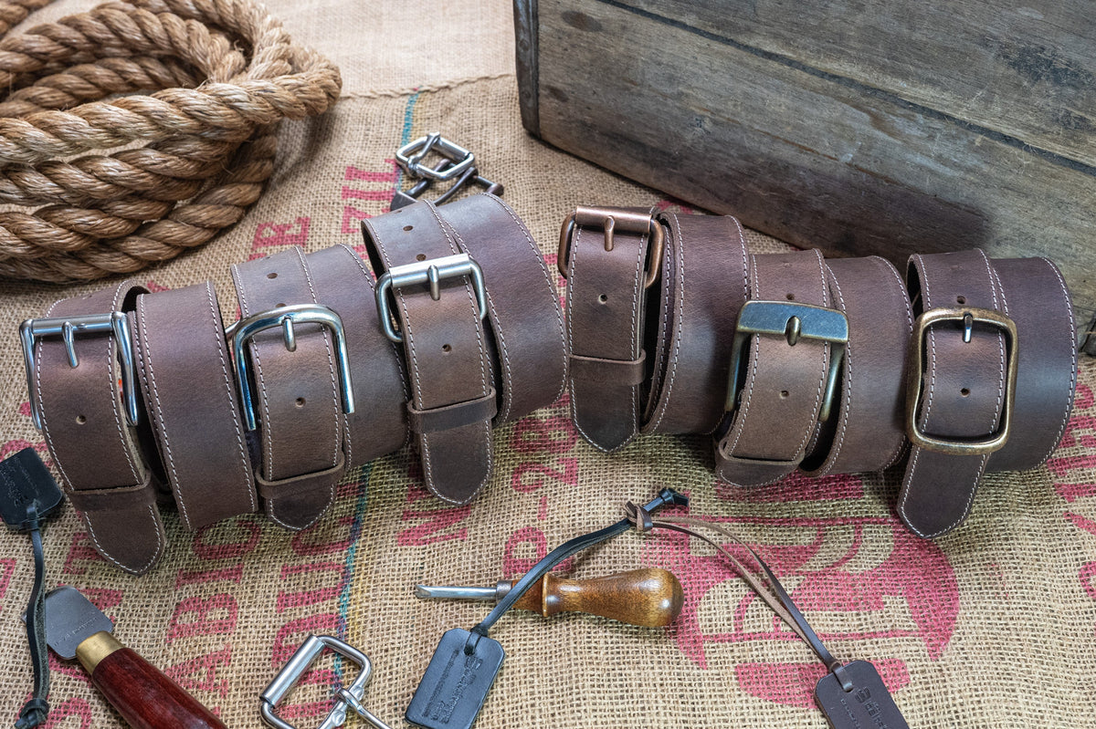 Set of leather belts with metal buckles on a rustic background