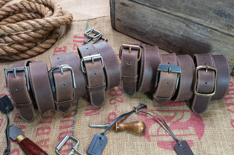 Set of leather belts with metal buckles on a rustic background