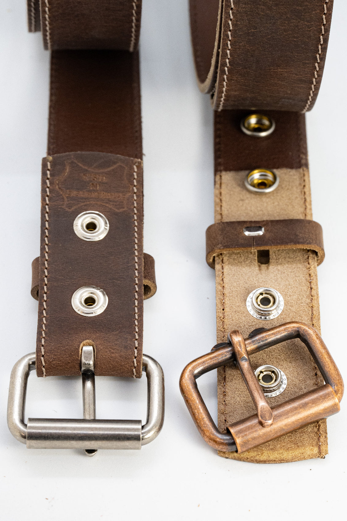 Two leather belts with metal buckles on a white background