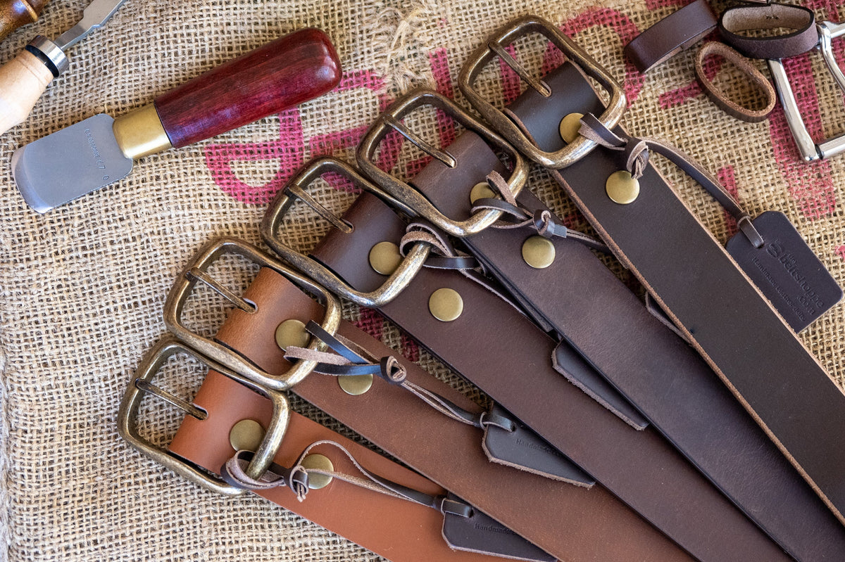 Set of leather belts with metal buckles on a textured fabric background