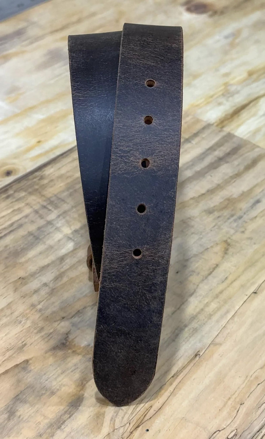 Dark brown leather belt on a wooden surface