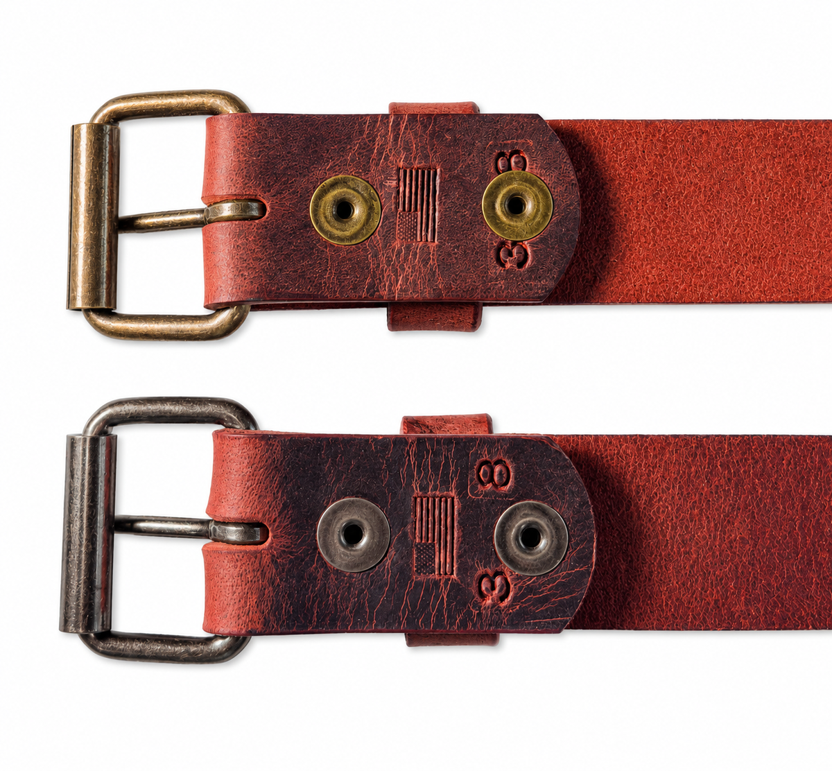 Undersides of two chestnut Crazy Horse leather belts with snap closures fastened behind antique brass and antique nickel roller buckles.
