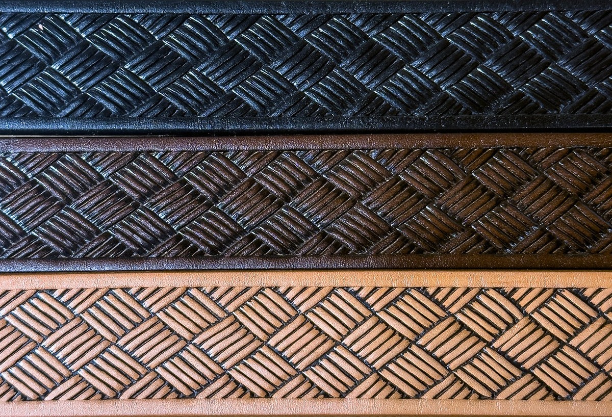 Close-up of black, brown, and tan steer hide leather belt straps laid parallel to compare their embossed basketweave pattern.