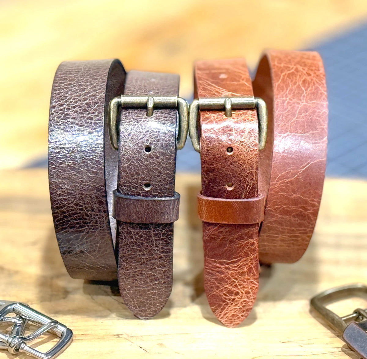 Brown and tan full grain buffalo leather belts on leather workbench