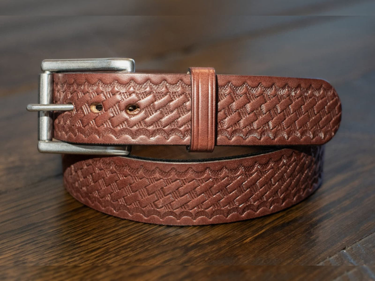 The Sheriff brown 1.5 inch Amish made full grain Wickett & Craig harness leather basket weave belt with stainless steel roller buckle on a wooden surface.