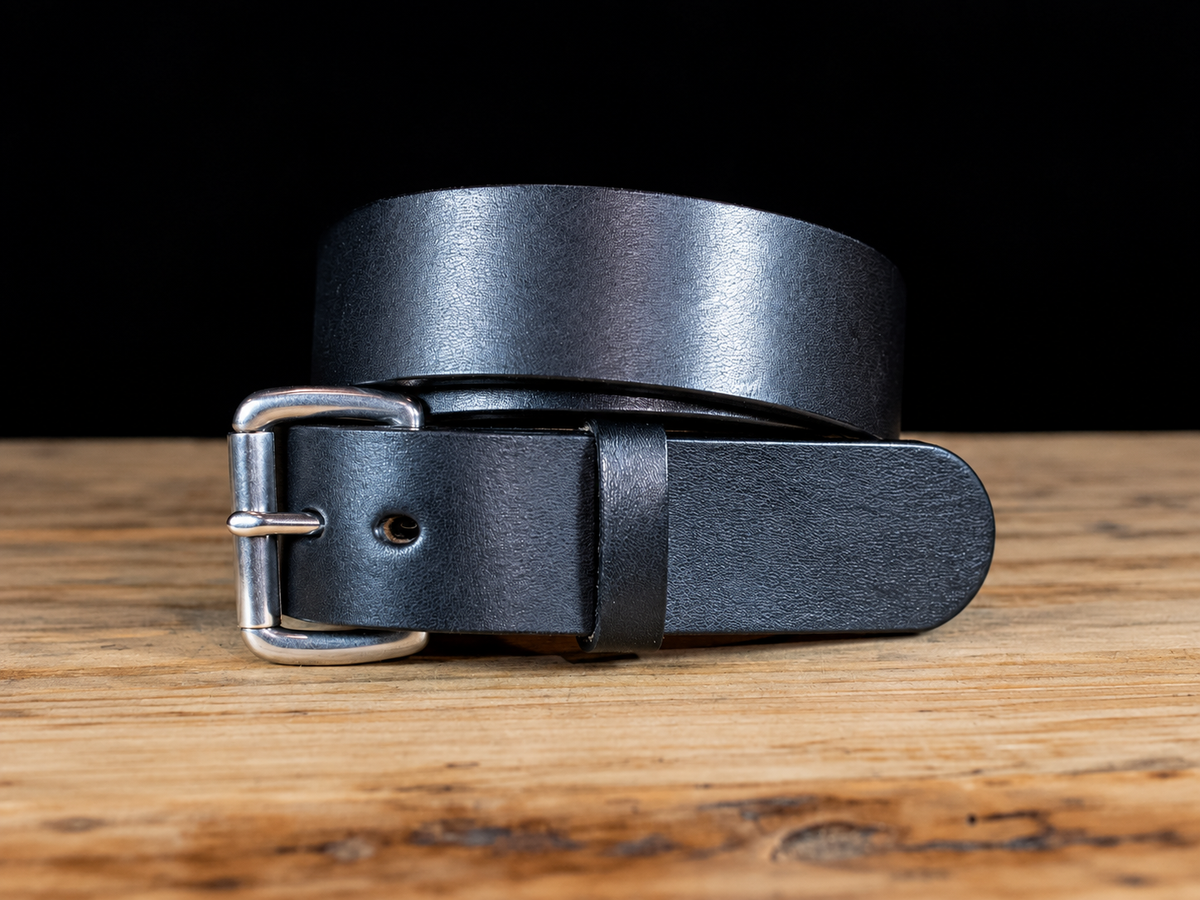 Black Workhorse thick full-grain Amish-made leather belt with silver roller buckle on a rustic wooden surface.