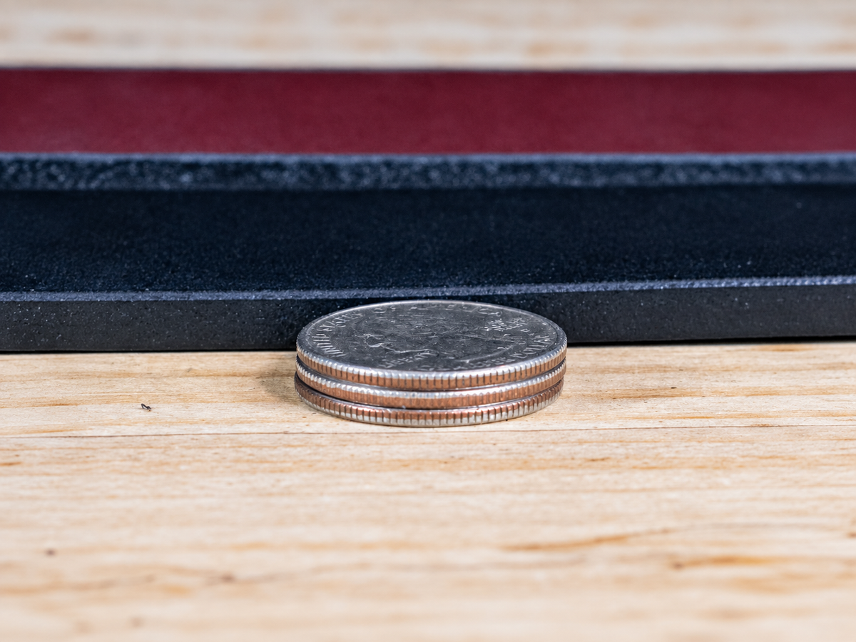 Stack of three coins beside Workhorse full-grain leather belt straps showing the substantial heavy-duty leather thickness.
