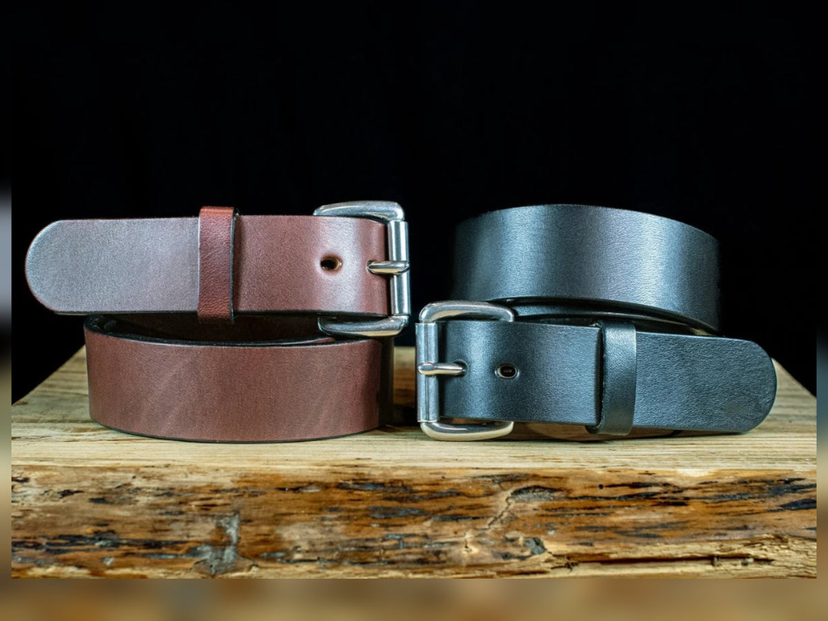 Black and brown Workhorse 1.5-inch full-grain leather belts coiled to show thick straps and silver roller buckles.