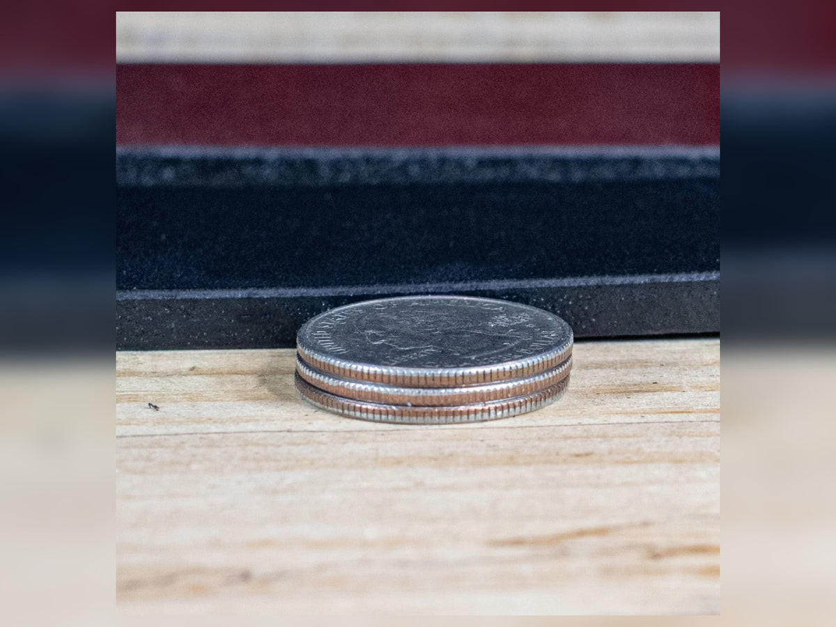 Stack of three coins beside Workhorse full-grain leather belt straps showing the substantial heavy-duty leather thickness.